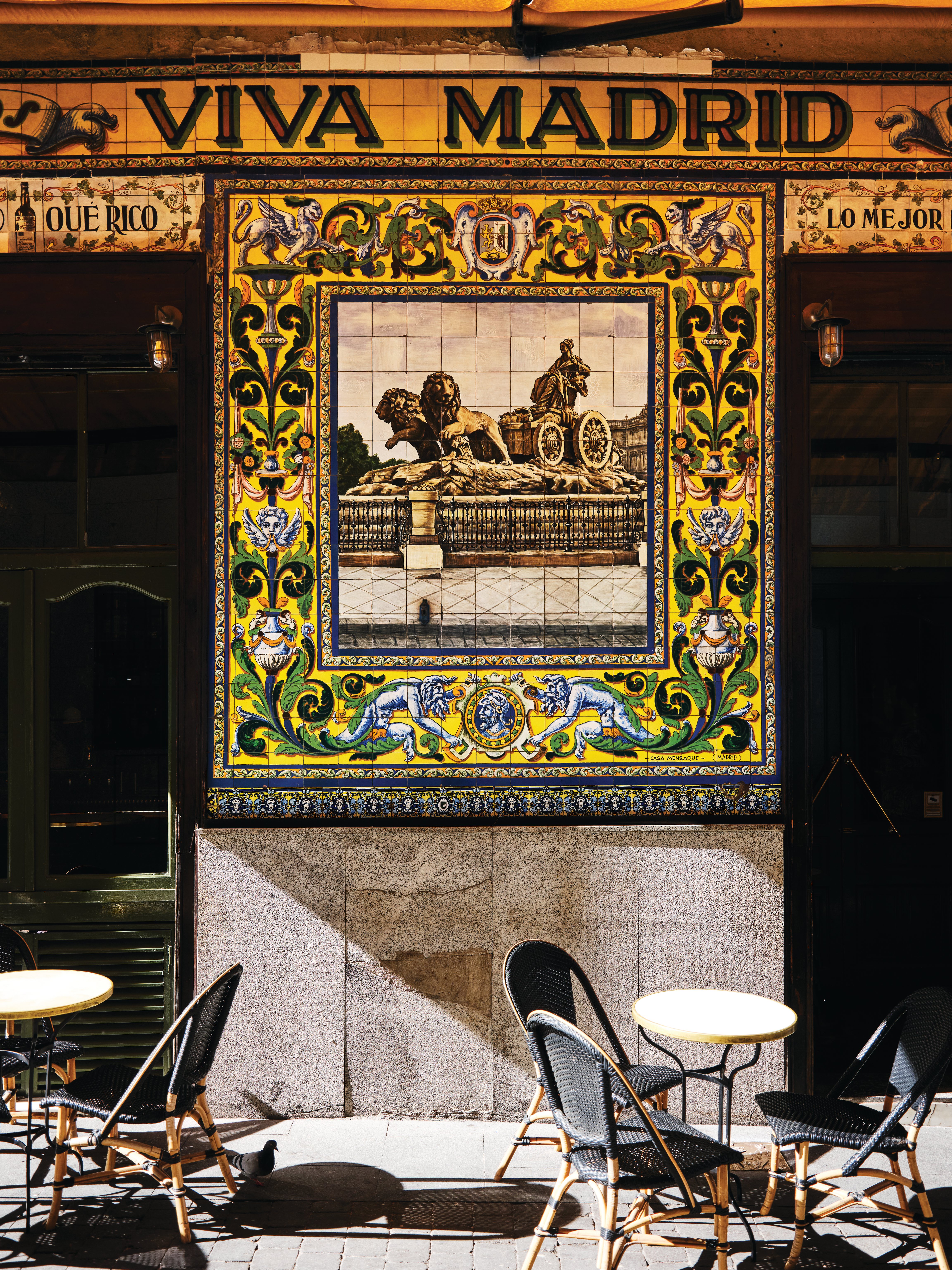 Colourful tiled Viva Madrid fa&ccedil;ade with outdoor caf&eacute; tables, evoking the Spanish food and travel atmosphere of Spain My Way.